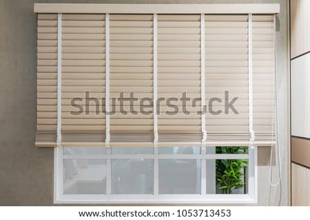 Sun-protection jalousie of white color on the window in a bright sunny day Royalty-Free Stock Photo #1053713453