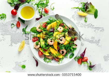 Fresh Avocado, Shrimps, Mango salad with lettuce green mix, cherry tomatoes, herbs and olive oil, lemon dressing. healthy food Royalty-Free Stock Photo #1053715400