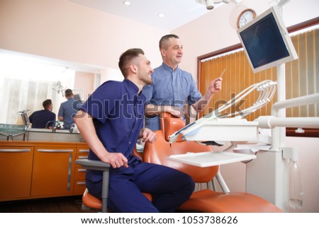 Two doctors in blue uniform in a dentist's office.