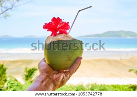 man hand with coconut cocktail in front of tropical beach, la digue, seychelles Royalty-Free Stock Photo #1053742778