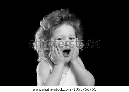 A black and white portrait of a little boy wearing a white tank top who looks surprised, excited and shocked. There is room for text and room for words on a solid black background.