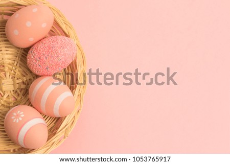 flat lay of colorful easter eggs with pastel pink shades in a wicker basket on pink background. Empty space for texts.