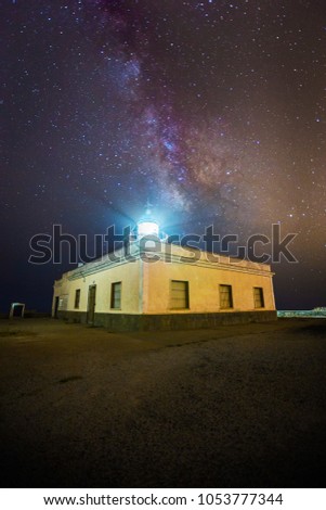 Milky Way in nigth sky over lighthouse and its light.