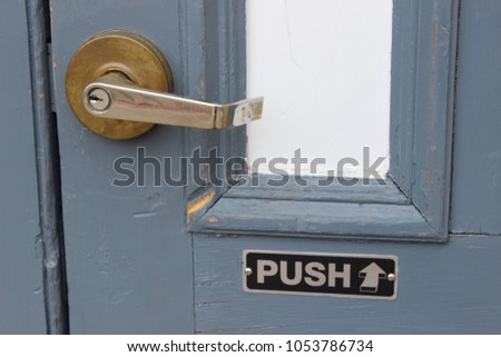 Push sign on blue weathered wooden  door of business building 