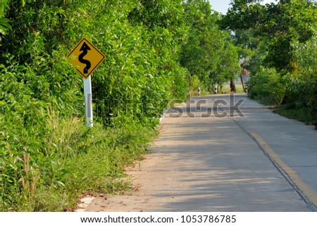curve road sign  in rural area, through the green tree background