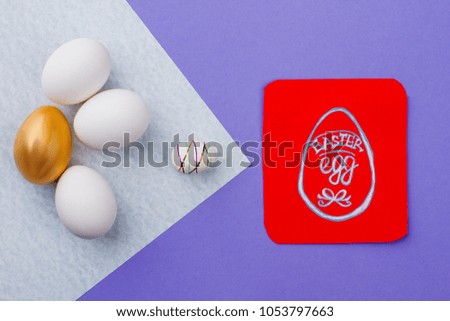 Easter composition with eggs and card. Red paper card with picture of Egg drawn by child. Golden egg among white eggs. Concept of happy Easter.