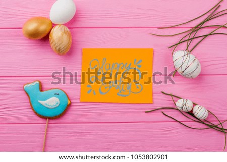 Happy Easter design on pink wood. White egg and golden eggs. Glazed Easter cookie and grass. Happy Easter card.