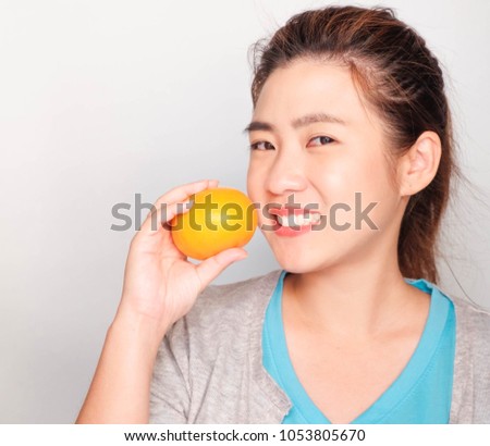 Close-up portrait friendly, Smiling asian woman wearing  blue t-shirt,
holding apple, orange, donut, milk and Vegetable, Health-care concept