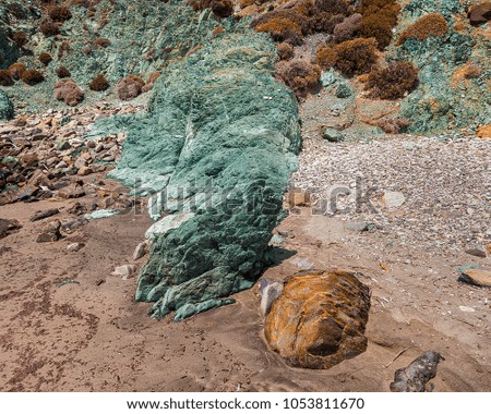 Coastal feature in Syros Island of natural green geological stone on the shoreline. Stock Photo.