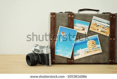 Image of old vintage luggage with vacation photos over wooden floor