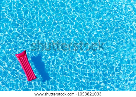 Pink inflatable mattress floating on water surface Royalty-Free Stock Photo #1053821033