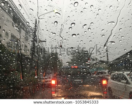Blurred background, raindrop on the windshield, traffic in the city on a rainy day, car windshield view, colorful bokeh.