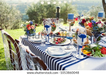 Lunch in the open air. Many dishes on the table. Design of a table in a marine style. Royalty-Free Stock Photo #1053860048