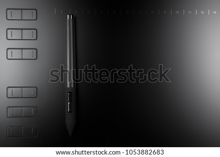 Graphic tablet with pen for illustrators and designers on black wooden background.