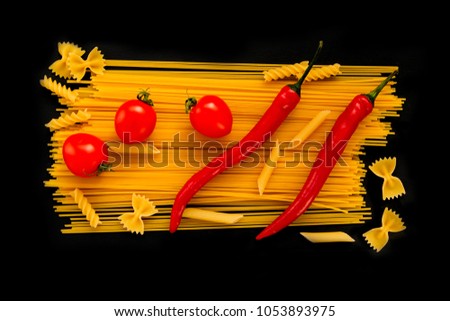 Macaroni of different types on a black background with tomatoes and hot peppers