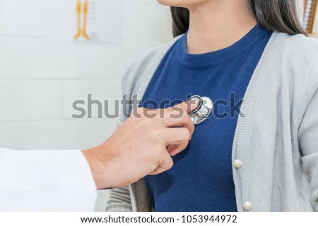 Close up of Doctor using stethoscope to exam heart and lungs of patient woman. Royalty-Free Stock Photo #1053944972