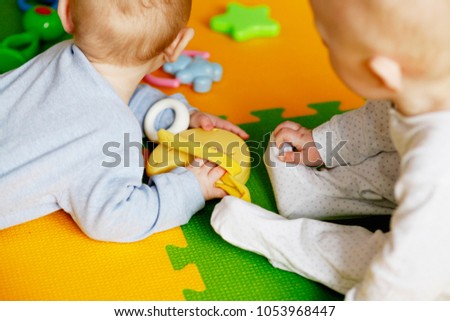 Two little twin infants lying and playing. Happy laughing kids, brothers playing together
