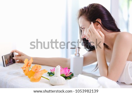 Beautiful young woman relaxing spa salon with selfi on mobile phone at spa resort