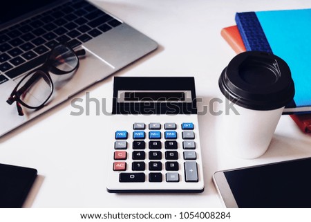 accounting basic tools. Calculator, smartphone, notebook, computer laptop and eyes glass on white table for startup in today.