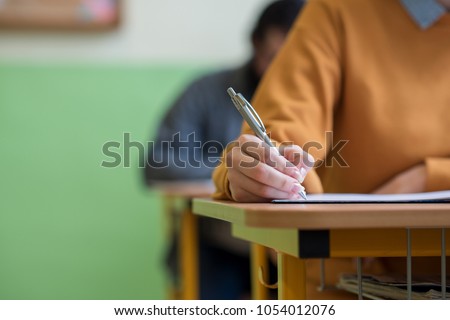 Students taking exam in classroom. Education test and literacy concept. Cropped shot, hand detail. Royalty-Free Stock Photo #1054012076