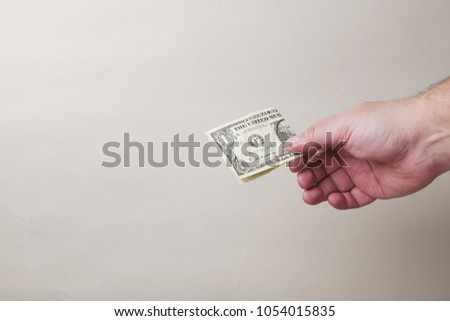 hand giviing one dollar banknote on gray background, copy space