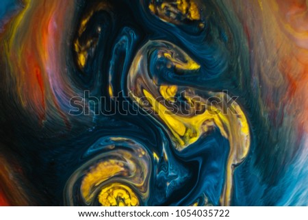 Abstract psychedelic background. Yellow ink is poured into a multicolored liquid with a slow motion