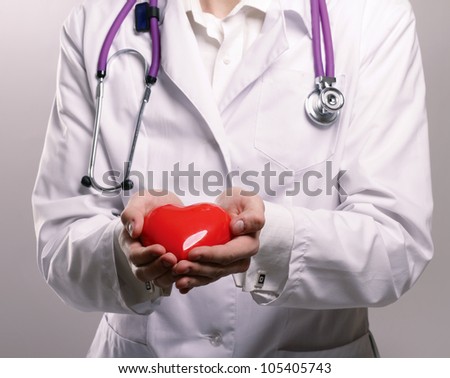 Male doctor with stethoscope holding heart on white background