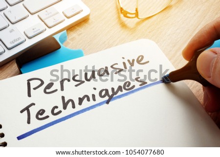 Man writing Persuasive Techniques in a note. Royalty-Free Stock Photo #1054077680