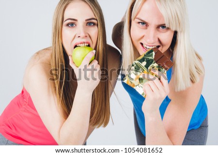 Young pregnant girl and her friend in a sports uniform eat an Apple and chocolate. The concept of a healthy lifestyle. Toning.