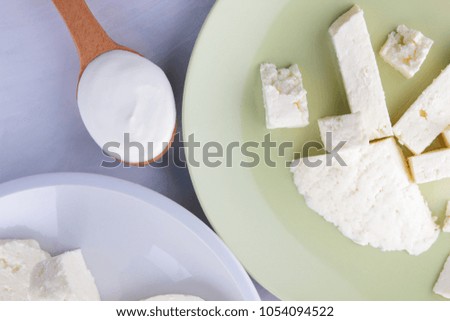 Cheese pattern, honey and sour cream, feta in white and green plate, soft cheese on a white background, wooden spoon with sour cream, French breakfast, blue napkin, honey in glassware