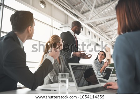 Low angle of managers sitting in the office and listening to speech of their partner Royalty-Free Stock Photo #1054114355