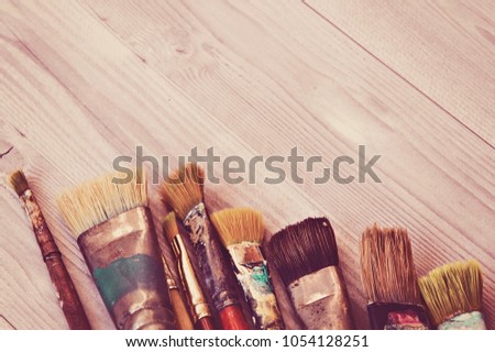 Brushes of the artist closeup on the background of a wooden table. Retro stylized.
