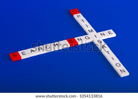 Search Engine Optimisation (SEO) made of white wooden blocks on blue background in crossword style, first letters are red