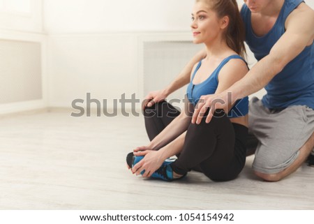 Fitness woman training with her personal trainer at gym. Young couple doing stretching exercises, copy space
