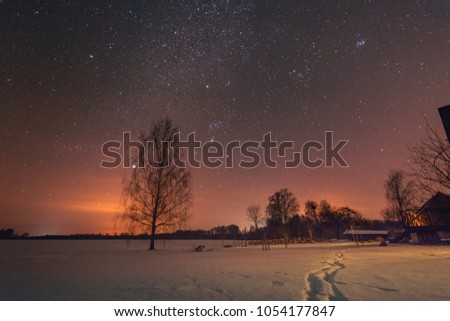 Sunset at night time with agricultural land in foreground and stars in background
