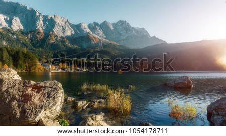 Awesome alpine highlands in sunny day. Nature Landscape. The Eibsee Lake in front of the Zugspitze under sunlight reflected in water. Majestic Autumn Scenery. Eibsee, Bavaria Germany. Retro Style