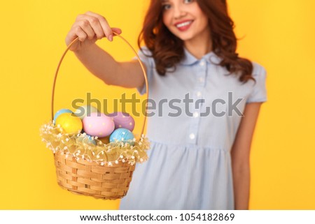 Young woman studio isolated on yellow holding basket with eggs close-up