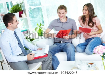Financial agent holding a meeting with a young family at home discussing the terms of the contract