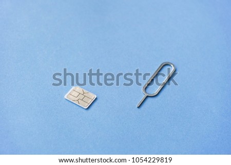 A Nano Sim Card and Eject Tool on Blue Background Royalty-Free Stock Photo #1054229819