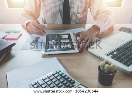 Businessman working with digital tablet and book and document on wooden desk in modern office.Top view Business analysis and strategy concept.