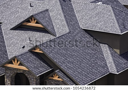 Rooftop in a newly constructed subdivision in Kelowna British Columbia Canada showing asphalt shingles and multiple roof lines Royalty-Free Stock Photo #1054236872