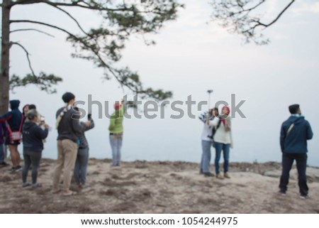Tourist is watching the sunrise and photograph selfie in the morning at the cliff blur background. 