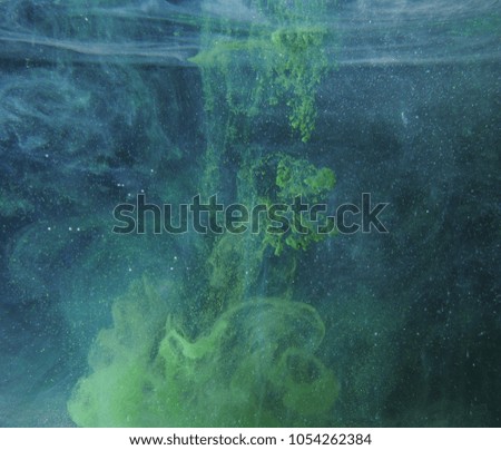 A drop of green paint dissolves in water. An abstract photo. Close up.