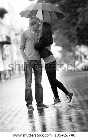 Young couple on the street of the city with umbrella. Photo in black and white style.