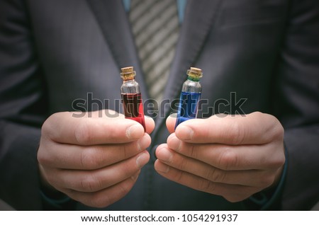 Blue and red pill essential liquid in business man hands. Choosing of right pill. Steroid or drug presentation. Medication for all diseases concept. Pharmacological or pharmaceutical business. Royalty-Free Stock Photo #1054291937