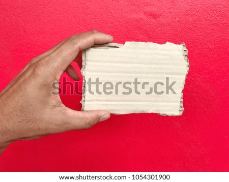 Close up hand hold brown paper card with red background. Business concept