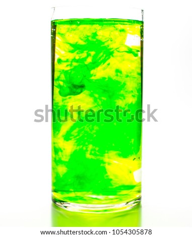 Green food coloring diffuse in water inside cylinder glass with empty copy-space area for slogan or advertising text message, over isolated white background.
