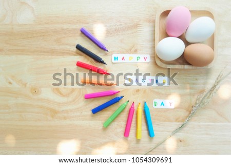 Many colorful pens and eggs are on the wooden table. The picture concepts for Easter, celebration, activity, hopefully with copy space.