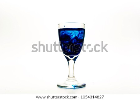 Blue food coloring diffuse in water inside wine glass with empty copy-space area for slogan or advertising text message, over isolated white background.