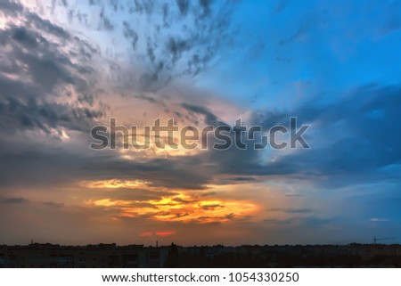 Sky and clouds at sunset over silhouettes buildings of the evening city.